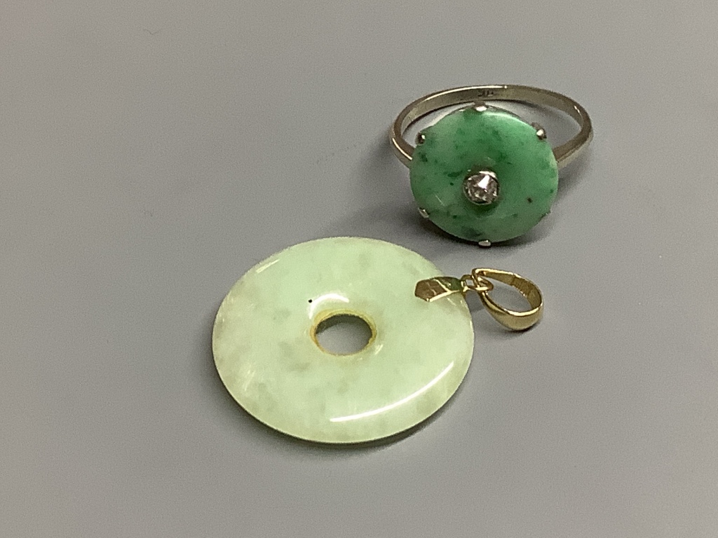 A 9ct white metal, jade and diamond set disc ring, size M, gross 2.1 grams and a 14k mounted jade disc pendant, gross 3.8 grams.